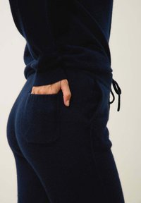 Navyblå stickad loungeklädesset med avslappnad passform, ribbade cuffs och en framficka på byxorna. Mjuk textur och avslappnad design.