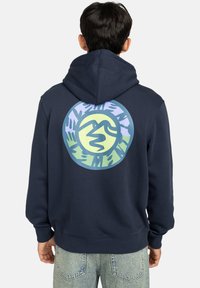 Felpa blu navy con una grafica circolare multicolore sul retro, caratterizzata da forme astratte e impronte delle mani. Tessuto di cotone con una vestibilità rilassata.