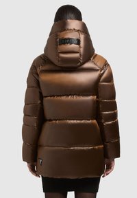 Jachetă puffer din bronz, cu guler înalt și design capitonat. Prezintă un logo pe glugă și un logo de accent pe lateral, aproape de margine.