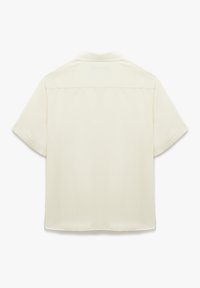 Camisa de manga corta en color crema claro, hecha de una tela suave, con un corte recto y una costura en el yugo trasero. Sin patrones ni acentos visibles.