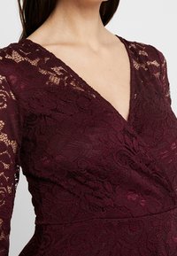 Burgundská krajková šaty s dlouhými rukávy, s hlubokým V výstřihem, květinovými vzory a texturovanou tkaninou. Elegantní a přiléhavý design.