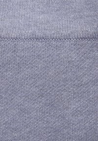 Šviesiai levandų spalvos mezginys, turintis lygų paviršių ir tekstūrą, su juostuotu raštu viršuje. Vienoda spalva su minimaliais variacijomis.