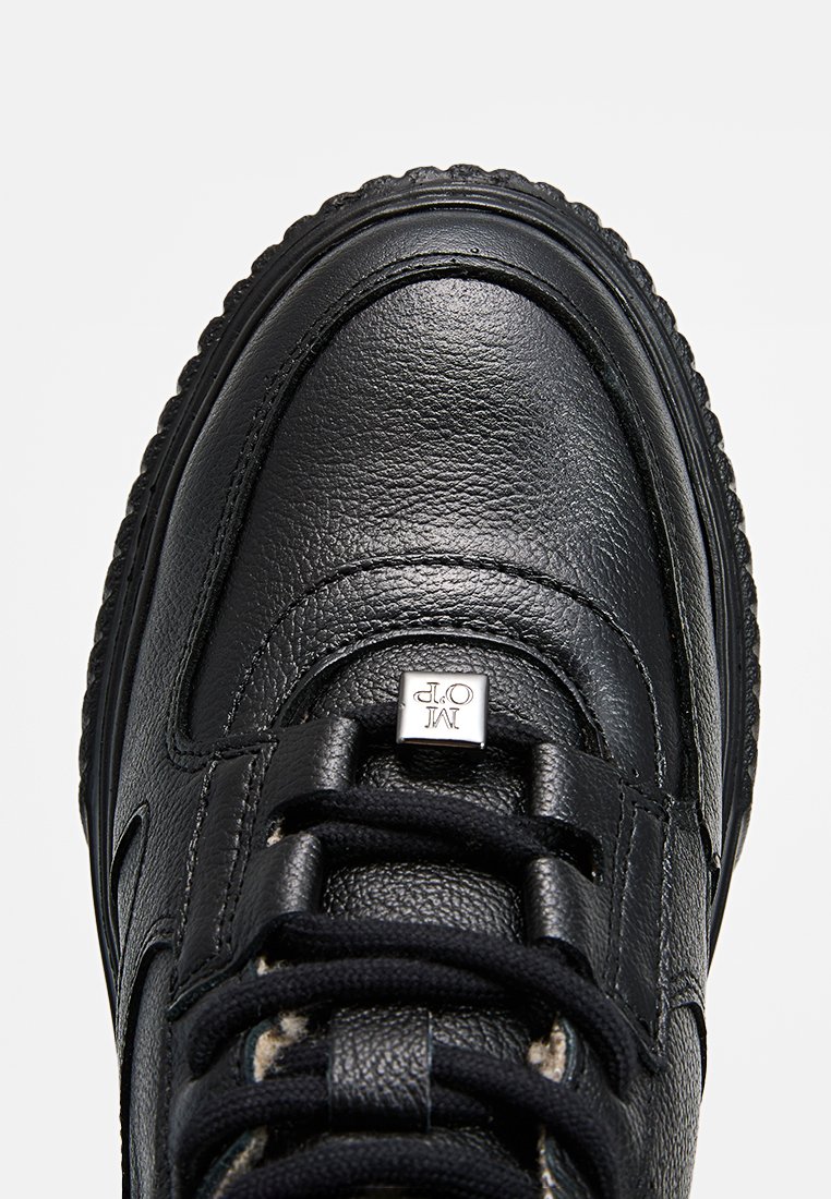 Czarne skórzane sneakersy z teksturowaną powierzchnią, wyraźnym systemem sznurowania i metalowym logo na języku.