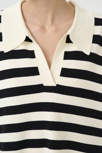 Juoda ir kreminė juostelėta polo marškinėliai su apykakle ir V formos iškirptė. Minkšta trikotažo medžiaga su lygiai išdėstytomis skirtingų pločių juostomis.