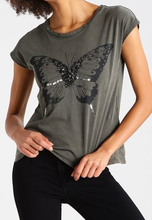Oliivinvihreä lyhythihainen t-paita, jossa on musta perhoskuvio, koristeltu paljeteilla. Rentoa istuvuutta ja pehmeä tekstuuri.