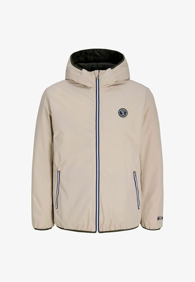 Veste à capuche beige avec fermeture éclair sur le devant, deux poches zippées, poignets élastiques et un patch rond noir avec logo sur la poitrine.