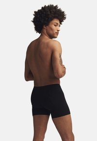 Svarta boxerkalsonger gjorda av stretchigt tyg, med en åtsittande passform, en bekväm midja och en slät textur, visade från en sidovinkel.