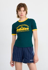 Green short-sleeve t-shirt with yellow accents and "adidas" graphic, paired with navy pinstriped shorts featuring white logo detail.