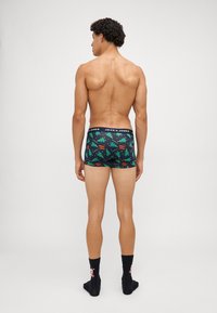 Férfi boxeralsó fekete derékrésszel, rajta a "JACK & JONES" márkával. Az anyag ünnepi mintázattal bír, zöld fák és színes részletek díszítik.