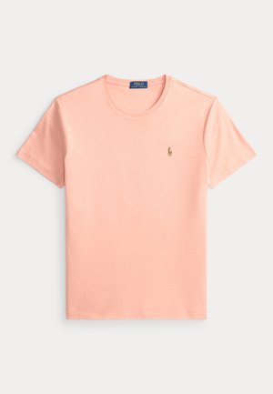 Svjetloružičasta majica s kratkim rukavima Polo Ralph Lauren s crew neck izrezom i malim izvezenim logom polo igrača na lijevoj strani prsnog koša.