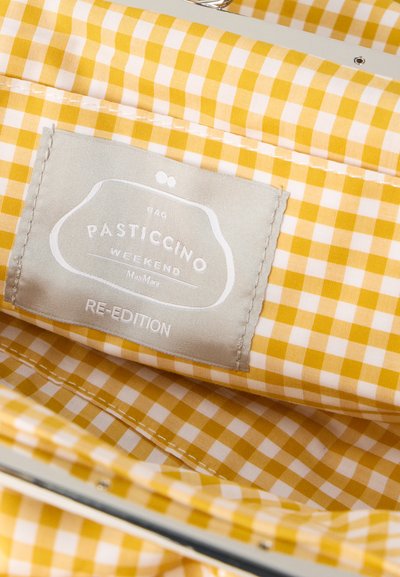 Intérieur d'un sac en tissu à carreaux jaune et blanc avec une étiquette grise cousue portant l'inscription "PASTICCINO WEEKEND RE-EDITION".