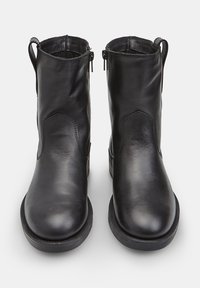 Melnas ādas potītes zābaki ar gludu tekstūru, noapaļotiem pirkstiem, šuvju detaļām un sānu rāvējslēdzējiem vieglai uzvilkšanai. Plakanas gumijas zoles.