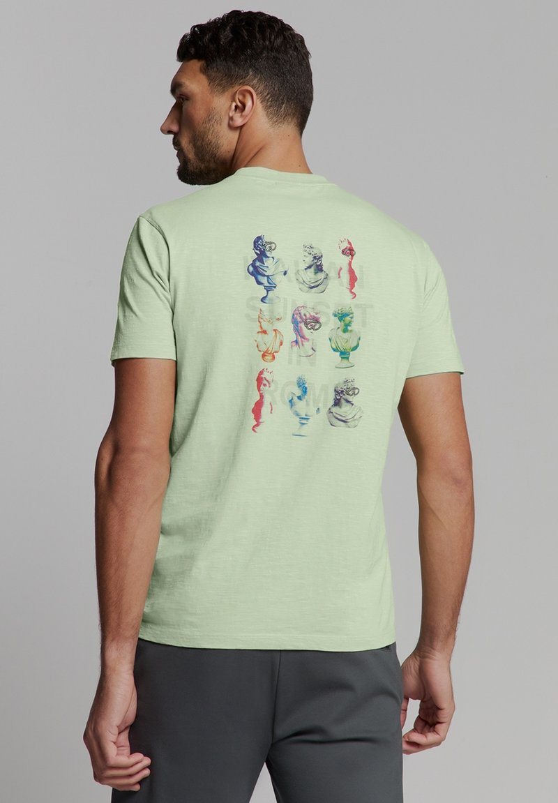 Lichtgroene T-shirt met korte mouwen, met kleurrijke artistieke borstafdrukken op de achterkant. Zachte textuur met een ontspannen pasvorm.