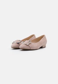 Ballerines en suède rose clair avec un petit talon carré, présentant une boucle carrée décorative et un motif texturé subtil au niveau des orteils.