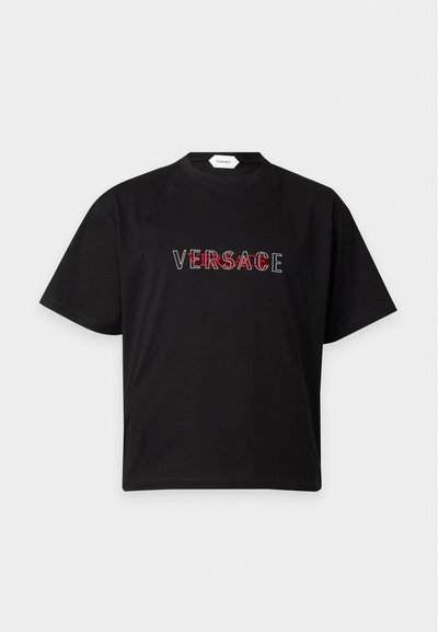 Μαύρο κοντομάνικο T-shirt Versace με κόκκινο και λευκό επικαλυπτόμενο κείμενο λογότυπου Versace στο στήθος και μικρή ετικέτα στον λαιμό.