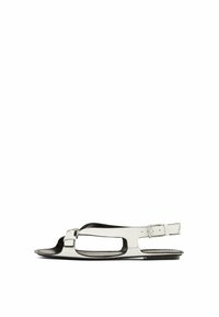 White leather sandal with a flat sole, open toe design, and side buckle strap. Features cut-out details along the sides.