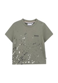 T-shirt verde a maniche corte in morbido cotone con stampa a spruzzi in grigio e bianco. Presenta un girocollo e dettagli con bottoni a pressione sulla spalla.