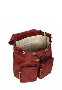 Zaino in tessuto rosso con parte superiore pieghevole, fodera beige, due tasche frontali con zip, hardware dorato e chiusura con cordino.