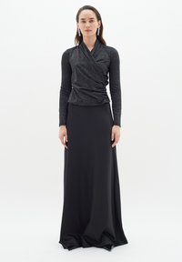 Abito da sera nero con top avvolgente scintillante e gonna liscia e fluida. Maniche lunghe e vestibilità snella esaltano l'eleganza.