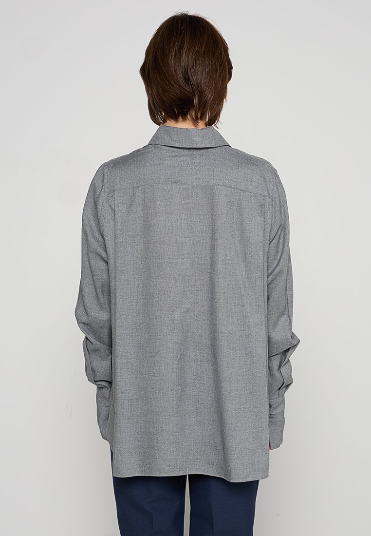 Grau langärmliges Hemd mit lockerer Passform und Rückenpasse. Der Stoff hat eine strukturierte Oberfläche und verfügt über einen klassischen Kragen sowie geknöpfte Manschetten.