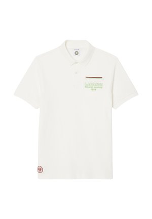 T-shirt polo blanc en coton avec un col. Présente un texte brodé vert et marron et une petite étiquette de logo sur l'ourlet.
