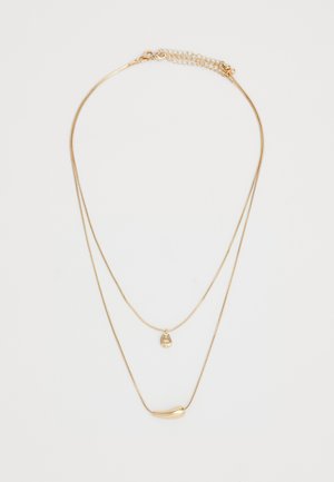 Collier en or à deux couches avec deux pendentifs lisses en forme irrégulière suspendus à de fines chaînes, sur fond blanc uni.