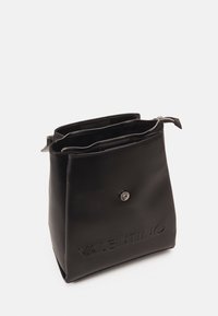 Černá kožená kabelka s pevnou strukturou, vyraženým logem a stříbrným kováním; obsahuje dvě oddělené přihrádky na zip a zapínání na druk.