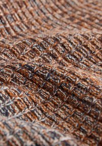 Tkanina o fakturze w odcieniach pomarańczowego, brązowego i kremowego, z wzorem plecionym tworzącym skomplikowany, warstwowy wygląd. Miękka, wełnista tekstura.