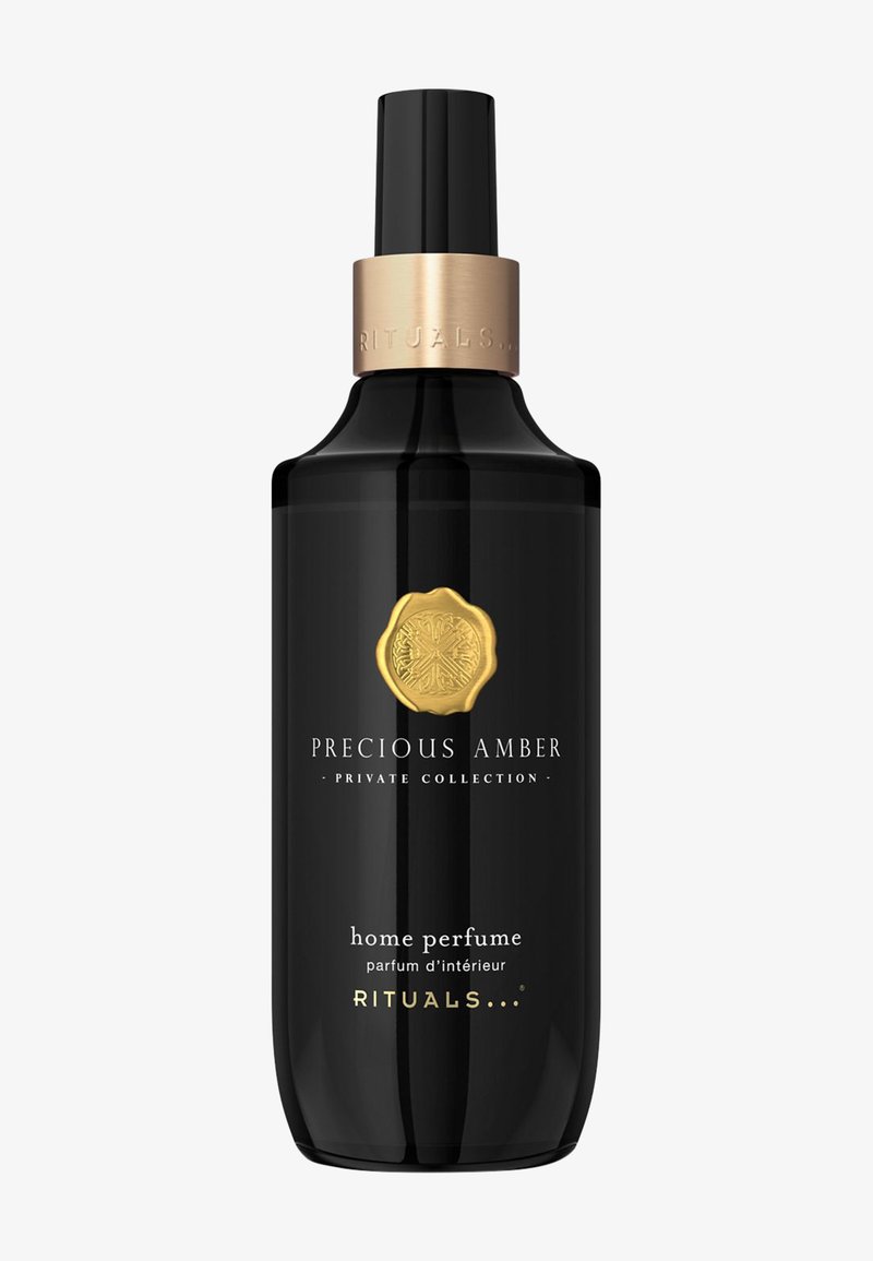 Bouteille de parfum pour la maison en verre noir avec un accent métallique doré, présentant la marque « Precious Amber » et « Rituals » en texte blanc.
