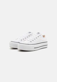 Weiße Canvas-Sneaker mit Gummisohle, runder Zehenpartie, Schnürdesign und schwarzen Streifenakzenten. Verfügt über Metallösen und eine strukturierte Zehenkappe.