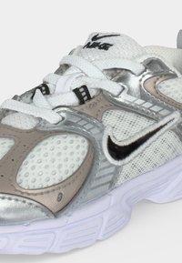 Λευκό και γκρι αθλητικό παπούτσι Nike με πάνελ από δίχτυ και δέρμα, λευκά κορδόνια και μαύρο λογότυπο Nike στο πλάι και στη γλώσσα.