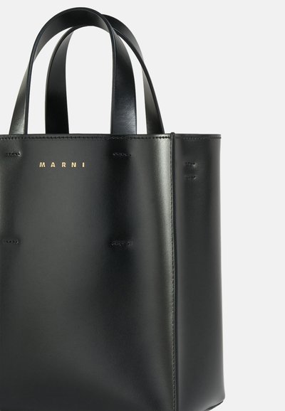 Borsa tote in pelle nera con forma strutturata, doppi manici e logo "MARNI" in rilievo dorato. Texture liscia con dettagli di cucitura minimi.