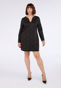 Rochie cu mânecă lungă și decolteu în V, cu un model de leopard în nuanțe de negru și marron închis. Materialul este neted și are o siluetă ajustată.