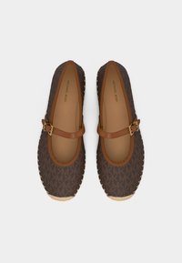 Καφέ μοκασίνια Michael Kors με ρυθμιζόμενο λουράκι και χρυσή αγκράφα, με σχέδιο λογοτύπου και υφαντή λεπτομέρεια στη μύτη και στις άκρες της σόλας.