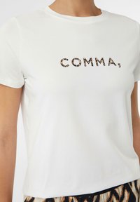 Weißes Baumwoll-T-Shirt mit dem Wort "COMMA" in fettem, braunem und schwarzem Leopardenmuster. Kurzarm und klassischer Rundhalsausschnitt.