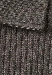 Tela de punto acanalado gris con una superficie texturizada y un detalle discreto de cremallera. El material parece suave y cálido, adecuado para climas fríos.