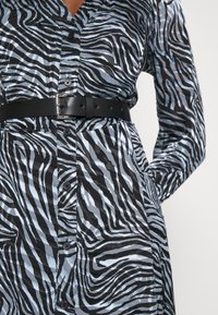 Randig skjortklänning i svart och ljusblått, med krage, knäppning fram och ett svart läderbälte i midjan.