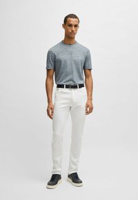 Szara, krótko rękawowa koszula z teksturowanej tkaniny, białe dopasowane spodnie i granatowe trampki z grubą kremową podeszwą. Czarny pasek ze srebrną klamrą.