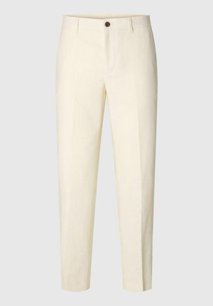 Pantalon sur mesure couleur crème avec un bouton à l’avant et des passants de ceinture, présenté sur un fond uni.