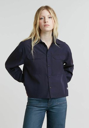 Navy blue button-up shirt with two chest pockets, long sleeves, relaxed fit, and a smooth, slightly shiny texture.