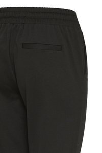 Fekete elasztikus nadrág gumis derékrésszel, hátsó zsebbel. Sima textúra, szabott varrással díszítve.