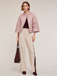 Gewatteerde, lichtroze cropped jas met een ronde kraag en knoopsluiting. Gecombineerd met crème wijde broek met burgundy zijstrepen.