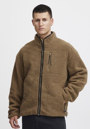 Brown fleece jacket with high collar, full zipper, and two side pockets. Features a textured exterior and a chest pocket with zipper detail.