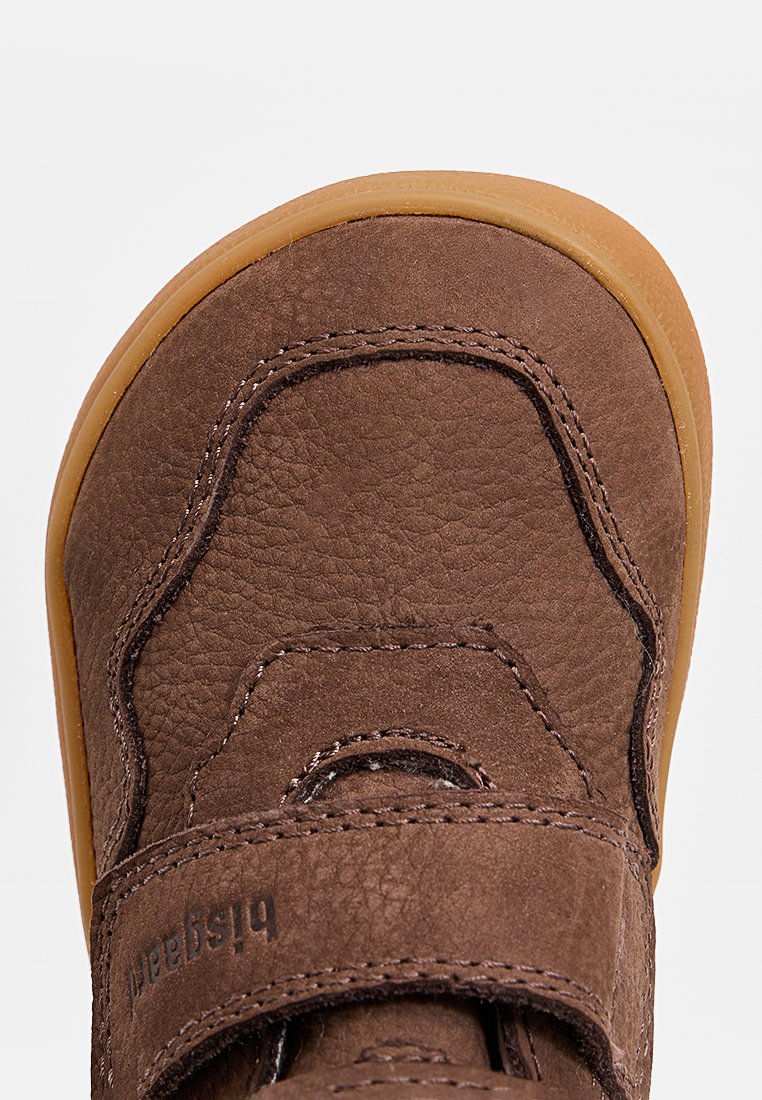 Chaussure en cuir marron avec une finition texturée, bout arrondi et semelle en caoutchouc. Elle dispose d'une sangle Velcro et de détails de couture.