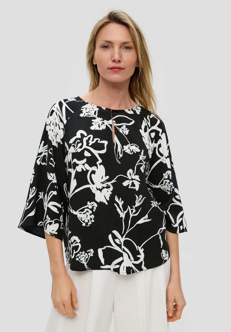 Zwarte top met wit bloempatroon, ronde halslijn en sleutelgaatje detail, met driekwart klokmouwen en een relaxte pasvorm.