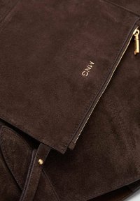 Braune Wildledertasche mit strukturierten Oberfläche, ausgestattet mit einem goldenen Reißverschluss und einem dezenten geprägten Logo. Das Design umfasst einen Klappdeckel und einen Druckverschluss.