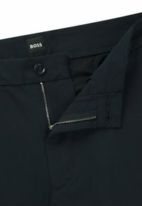 Navy trousers with a button closure and zip fly, featuring a smooth texture and the BOSS logo label on the waistband.