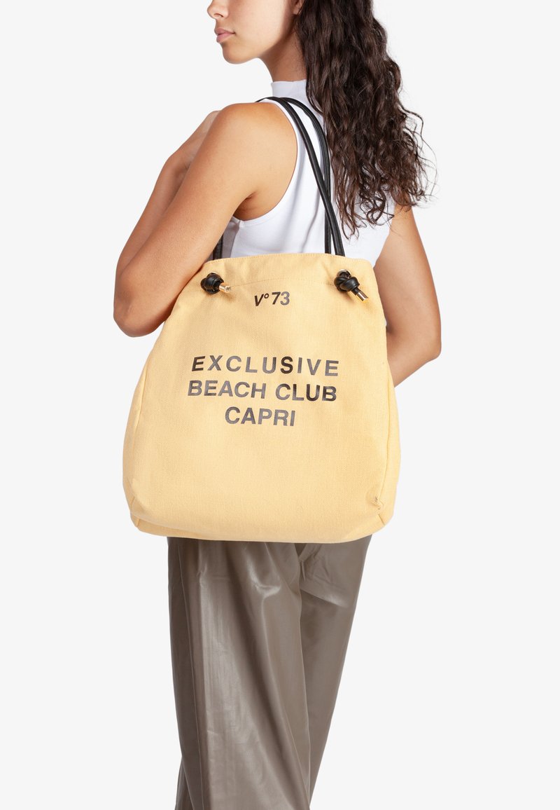 Borsa tote in tela gialla con testo nero "EXCLUSIVE BEACH CLUB CAPRI", dotata di due spallacci neri e chiusura con laccio.