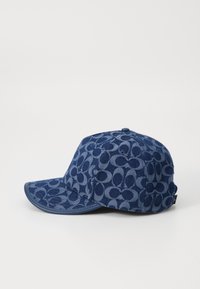 Denim kapa za baseball v temno modri barvi s vzorčeno površino, ki prikazuje kroge. Ukrivljen vizir in gumb na vrhu. Teksturni material.