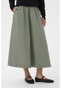 Light green, knee-length skirt with an elastic waistband and side pockets, paired with black flats. Smooth, lightweight fabric.